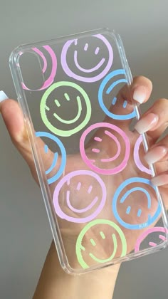 a hand holding a clear case with smiley faces on it