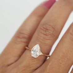 a woman's hand with a ring on it and a pear shaped diamond in the middle