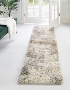 a white and gray area rug in front of a door with a plant on it