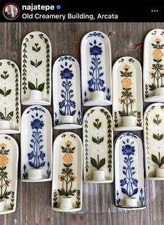 twelve blue and white plates with flowers painted on them are lined up against a wooden table