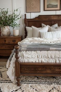 a bed with white linens and pillows in a small room next to two wooden dressers