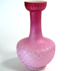 a pink vase sitting on top of a white table