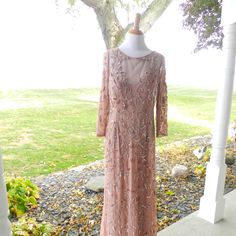 a dress on a mannequin in front of a tree with grass and rocks