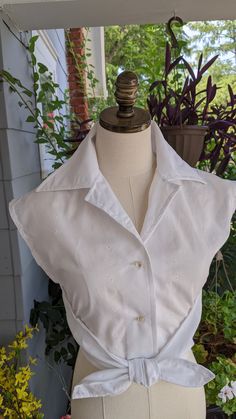 Wrapped blouse from a 1970's Butterick sewing pattern. Handmade by me. Sits at waist. Front buttoned closing, extended shoulders, elasticized front waist.  Measurements of the final garment are: 34 inch chest, 26 inch waist (will stretch)  18 inch length, Back waist 16 1/2 inch. Elastic is attached to the front sides. Elastic goes around waist in back, button blouse in front. Bring the tie ends to front and tie into knot. Fitted Blouse 1970s Style For Summer, Fitted 1970s Style Summer Blouse, 1970s Style Fitted Cotton Blouse, Vintage Cropped Top With Buttons, Retro Style Fitted Blouse For Daywear, Retro Fitted Blouse For Daywear, Fitted Retro Blouse For Daywear, Retro Fitted Tops For Daywear, Vintage Fitted Cropped Blouse