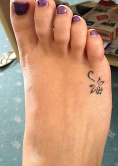 a woman's foot with a small flower tattoo on her left toe and purple nail polish