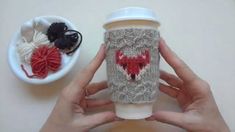 someone is holding a coffee cup in front of a knitted mug cozying it up