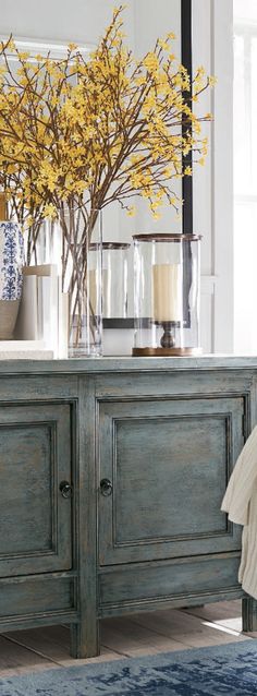 a blue and white dresser with yellow flowers in it's centerpiece on top