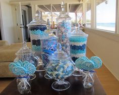 a table topped with lots of blue and white candies on top of glass vases