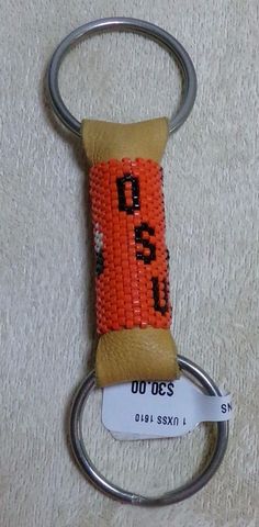 an orange beaded keychain with the word oasis on it is attached to a metal ring