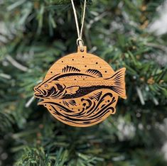 a wooden ornament hanging from a christmas tree with fish and waves on it