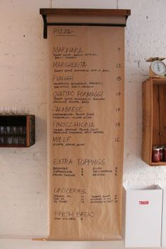 a wooden menu hanging on the wall next to a clock and other items in front of it