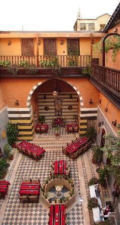 an outdoor courtyard with tables and benches in the center, surrounded by potted plants