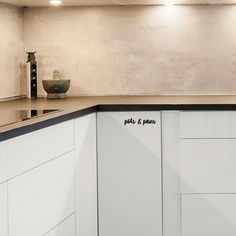 a kitchen with white cabinets and black lettering on the wall