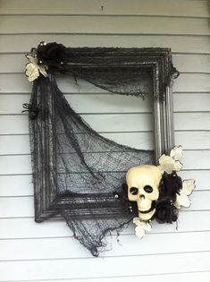 a skull and flower decoration hangs on the side of a white house with black netting