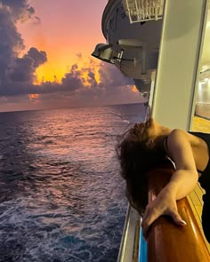 a woman is sleeping on the deck of a boat at sunset or sunrise, with her eyes closed