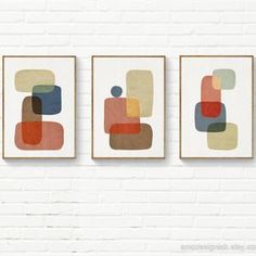 three framed art pieces hanging on a wall next to a brick wall with white bricks