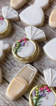 some decorated cookies are sitting on a wooden table with white icing and pink flowers