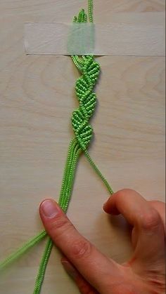 someone is making something with green string