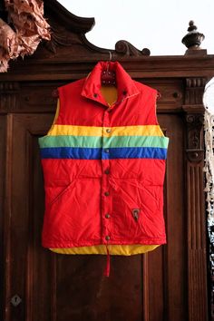 Amazing Swedish Vintage quilted puffer vest from the 1980s! Soft and warm down filling. Red color with bold horizontal rainbow stripes on the front, the back and the collar. Contrasting yellow lining. Branded metal snap buttons, two side pockets. Leather brand patch on the left pocket. Tie band in the waist. ERA: 1980s BRAND: Design Stefan Vestberg COLOR: Red, yellow, green, blue FABRIC: 65% polyester, 35% cotton, down padding SIZE: Vintage size 38, fits best size S-M, please check the measurements below for reference MEASUREMENTS: Pit to pit 52cm, total length without collar: 63cm on the front, 70cm on the back CONDITION: Very good Vintage condition Retro Red Winter Vest, Red Retro Winter Vest, Ski Vest, Quilted Puffer Vest, Warm Down, Vest Outfits, Vintage Quilts, Puffer Vest, Rainbow Stripes