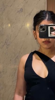 a woman taking a selfie in front of a mirror with her cell phone up to her face