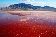 the red water is reflecting the mountains in the distance