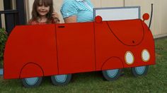 two children are standing behind a cardboard firetruck that is made to look like a car