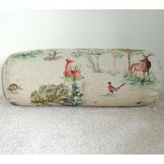 a roll pillow with animals on it sitting on the floor in front of a wall