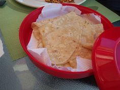 some tortilla chips in a red bowl on a table