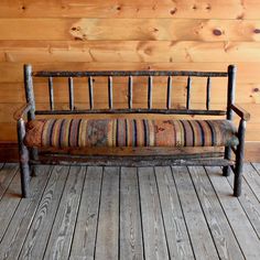 an old wooden bench sitting in front of a wood paneled wall with planks