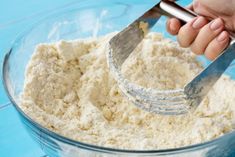 someone is mixing flour in a glass bowl