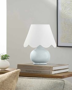 a white lamp sitting on top of a table next to two books and a vase