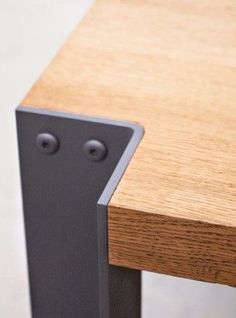 a close up view of a wooden table with two metal legs and an angled edge