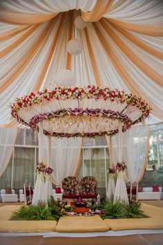 an elaborate canopy decorated with flowers and greenery for a wedding ceremony or reception area