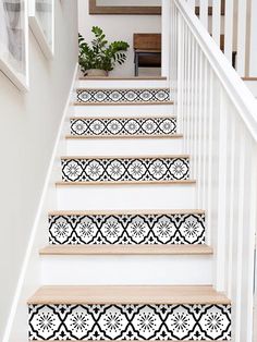 the stairs are decorated with black and white tile designs, along with potted plants