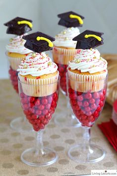 some cupcakes with white frosting and red candy in them on a table