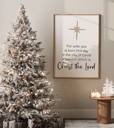 a white christmas tree in a living room next to a framed poster with the words, christ the lord