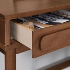 a close up of a wooden table with magazines on the top and bottom drawer open