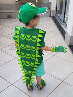 a little boy in a green alligator costume