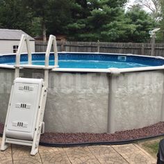 an above ground swimming pool with ladders next to it and a fenced in back yard