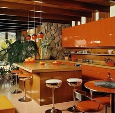 a kitchen with orange cabinets and stools next to an island in front of a window