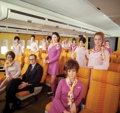 an airplane cabin with many people sitting on the seats and one man standing in front