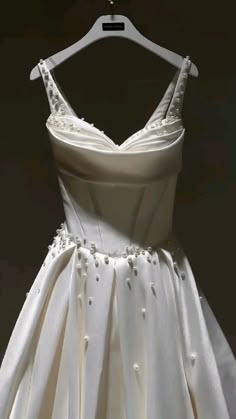 a white dress hanging on a hanger in front of a black background with the back of it's neckline