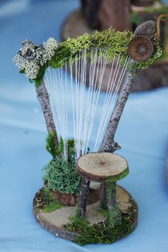 a wooden stand with plants and trees on it's sides, sitting on top of a blue table cloth