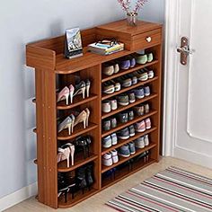 a wooden shoe rack with many pairs of shoes on it next to a door and rug