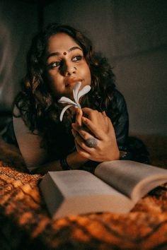 a woman laying on top of a bed with an open book next to her face