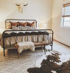 a bed room with a neatly made bed and a cow skull on the wall