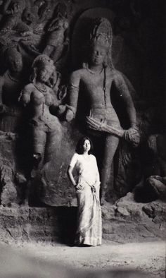 an old black and white photo of a woman standing in front of statues