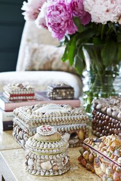 a table topped with lots of jewelry next to a vase filled with pink and white flowers