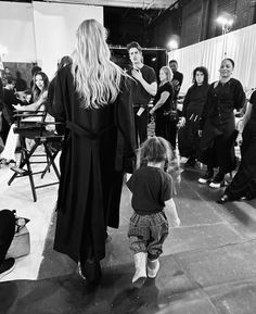 a black and white photo of a woman walking with a child in front of her