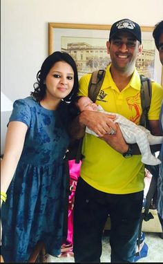 three people standing next to each other holding a baby